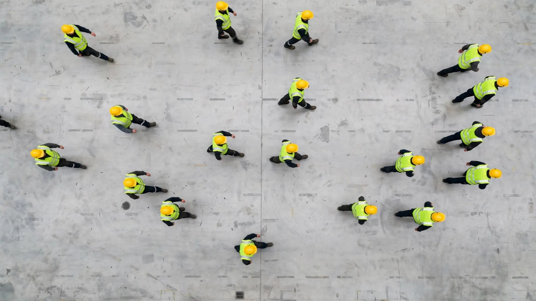 Overhead view of factory workers in high-visibility vests crossing a plant floor